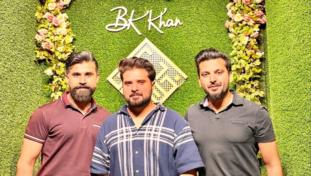 BK Khan's BBQ team posing in front of the signature green logo wall