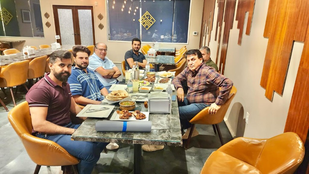 Guests enjoying a family-style dinner with tandoori chicken and naan at BK Khan's BBQ